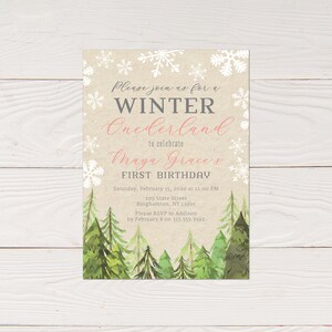Puede incluir: Una invitaci&oacute;n de primer cumplea&ntilde;os de Winter Onederland con una escena de bosque en acuarela en la parte inferior. La invitaci&oacute;n presenta copos de nieve y el texto "Please join us for a Winter Onederland to celebrate Maya Grace's First Birthday."
