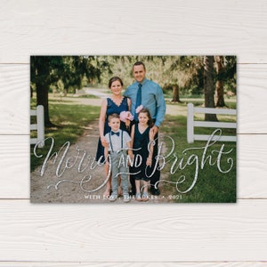 May include: A family portrait on a holiday card with the words "Merry and Bright" in silver script. The family of four is standing on a path, with trees and a white fence in the background. The card reads "With Love, The Lukes 2021".