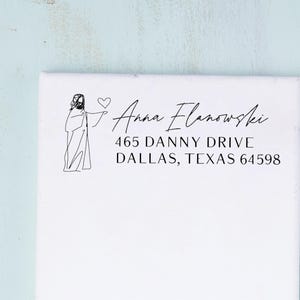 May include: White canvas with black text and a line drawing of a figure. The text reads "Anna Flanowski" above an address: "465 Danny Drive, Dallas, Texas 64598."
