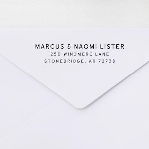 May include: White envelope with black text. The text reads: MARCUS & NAOMI LISTER, 250 WINDMERE LANE, STONEBRIDGE, AR 72738. The envelope is folded at the bottom right corner.