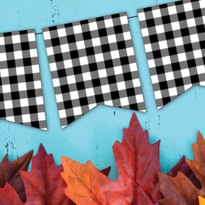 Peut inclure: Guirlande &agrave; carreaux noirs et blancs sur fond bleu. La guirlande est suspendue en haut de l'image et il y a des feuilles d'automne rouges et orange en bas de l'image.