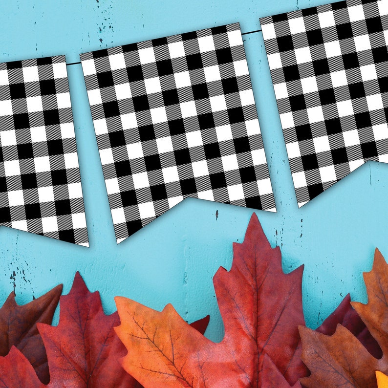 Peut inclure: Guirlande &agrave; carreaux noirs et blancs sur fond bleu. La guirlande est suspendue en haut de l'image et il y a des feuilles d'automne rouges et orange en bas de l'image.