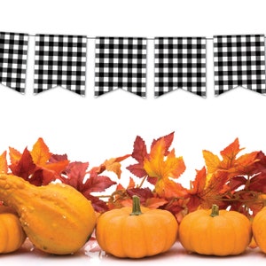 Peut inclure: Une banni&egrave;re de fanions &agrave; carreaux noirs et blancs avec une rang&eacute;e de feuilles d'automne orange et rouges et des courges en bas de l'image.