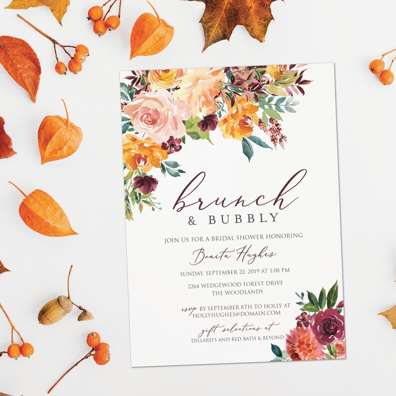 May include: A bridal shower invitation with the words "brunch & bubbly" in a cursive font. The invitation features floral arrangements in shades of orange, peach, and burgundy. The invitation includes details for the event, including the date, time, and location.