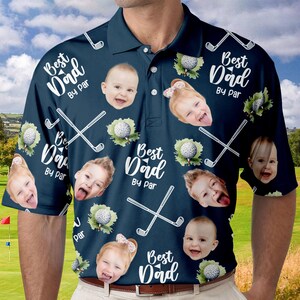 Puede incluir: Una camisa de golf azul marino con un patr&oacute;n repetido de palos de golf, pelotas de golf y el texto "Best Dad By Par". La camisa presenta varias fotos de caras de ni&ntilde;os.