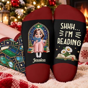 May include: A pair of dark red and black socks. One sock features a cartoon character reading a book in front of a stained glass window with the name Jessica below. The other sock displays the text SHHH... I'M READING above an open book with daisies.
