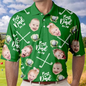 Puede incluir: Camiseta polo verde de tem&aacute;tica de golf con un patr&oacute;n repetido de palos de golf, pelotas de golf y caras de ni&ntilde;os. El texto "Best Dad By Par" se repite en toda la camiseta.