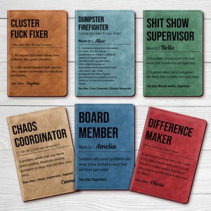 May include: A collection of six leatherette notebooks with humorous titles and definitions. Titles include "Cluster Fuck Fixer," "Dumpster Firefighter," and "Shit Show Supervisor." Each notebook has a different color and a unique definition.