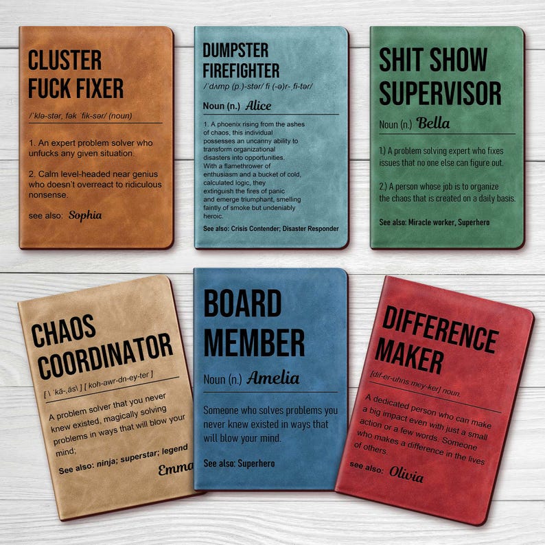 May include: A collection of six leatherette notebooks with humorous titles and definitions. Titles include "Cluster Fuck Fixer," "Dumpster Firefighter," and "Shit Show Supervisor." Each notebook has a different color and a unique definition.