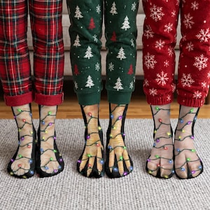 Puede incluir: Tres pares de calcetines con estampados realistas de patas de animales envueltos en luces de colores. Los calcetines se llevan con pantalones de pijama de cuadros rojos, con motivos de árboles de Navidad verdes y de copos de nieve rojos.