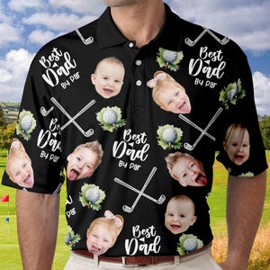 Puede incluir: Camiseta de golf negra con una impresi&oacute;n blanca que dice "Best Dad By Par" y presenta un patr&oacute;n repetido de palos de golf, pelotas de golf y caras de ni&ntilde;os.