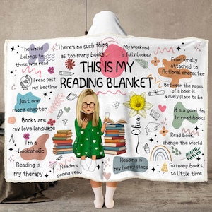 May include: A white fleece blanket featuring the text THIS IS MY READING BLANKET, a central illustration of a person with blonde hair in a green dress reading a book, stacks of books, a yellow flower, and various phrases about reading.