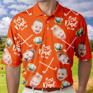 Puede incluir: Camiseta polo naranja de tem&aacute;tica de golf con un patr&oacute;n repetido de palos de golf, pelotas de golf y el texto "Best Dad By Par". La camiseta presenta m&uacute;ltiples im&aacute;genes de caras de ni&ntilde;os.