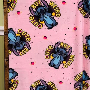 Pu&ograve; includere: Coperta in pile rosa con un motivo ripetuto del personaggio Stitch di Lilo & Stitch. Ogni Stitch &egrave; circondato dalle parole "Cute But Weird", con piccoli pianeti rosa sparsi sullo sfondo.