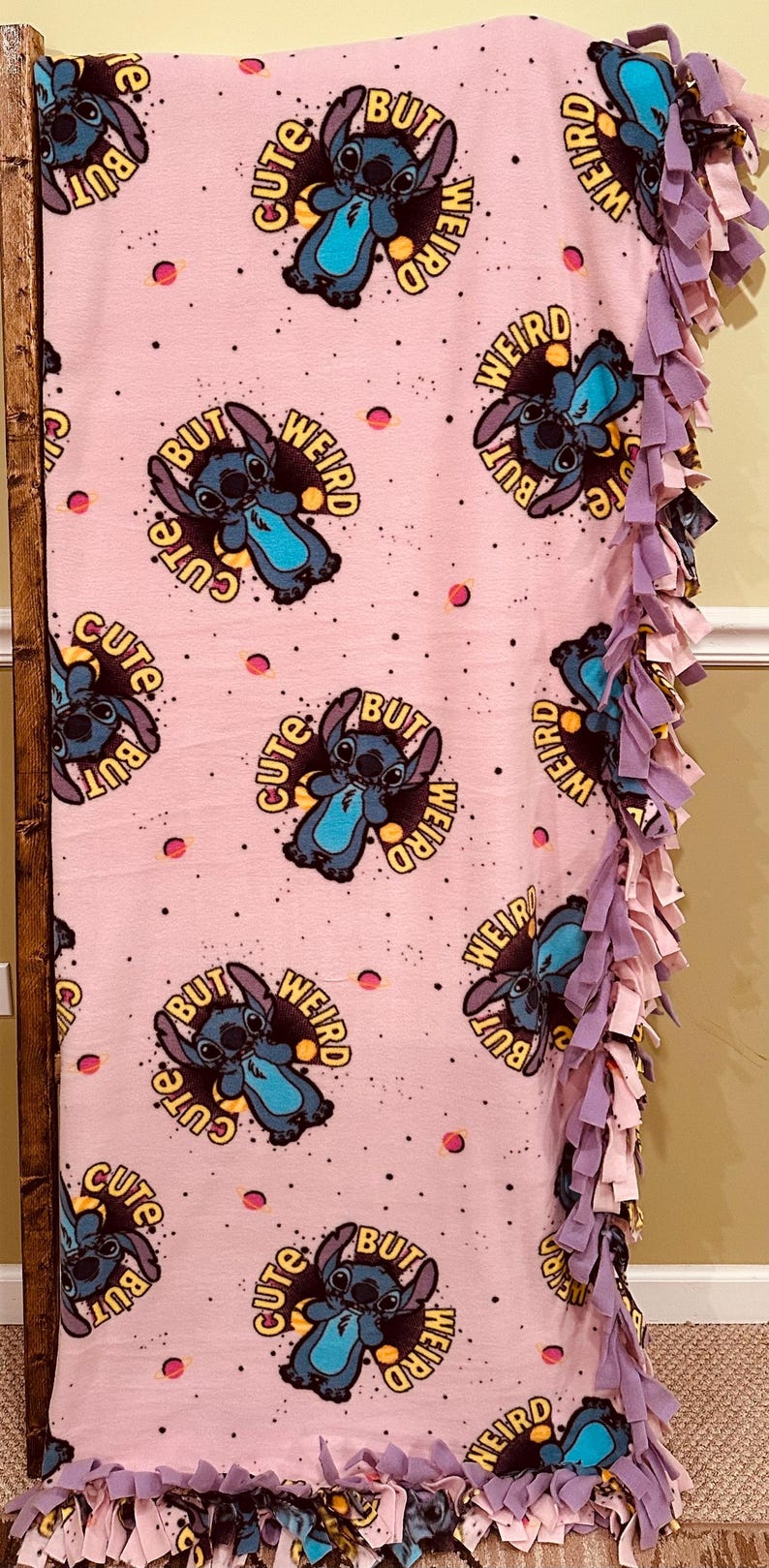 Pu&ograve; includere: Coperta in pile rosa con un motivo ripetuto di un personaggio dei cartoni animati e la scritta "Cute But Weird". La coperta ha un bordo sfrangiato nei toni del viola e del rosa. Un plaid accogliente.