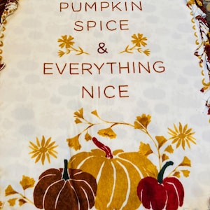 May include: White fleece blanket with a brown, red, and yellow pumpkin design. The blanket has a frayed edge and says "Pumpkin Spice & Everything Nice".