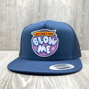 May include: Navy blue trucker hat with a mesh back and a flat brim. The hat features a patch with the text "WHY DON'T YOU BLOW ME" in a bubble design with pink and white accents. The hat has a snapback closure.