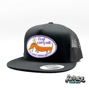 May include: Black trucker hat with a purple and orange embroidered patch that says "It's not a party until the wiener comes out." The patch features a cartoon dachshund wearing a party hat and sunglasses.