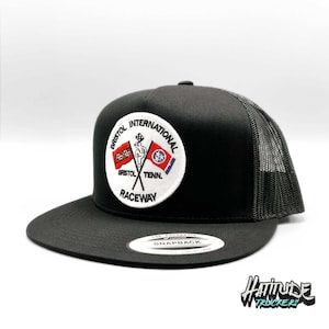 May include: Black and gray trucker hat with a white patch that says "Bristol International Raceway" with a checkered flag and two flags. The hat has a black mesh back.