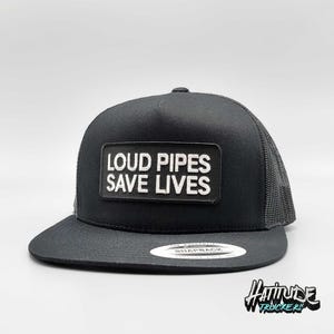 Puede incluir: Gorra de camionero negra con un parche blanco que dice "Loud Pipes Save Lives".