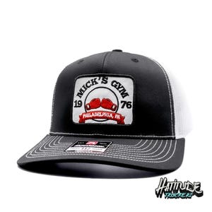 May include: Black and white trucker hat with a black and white patch that says "Mick's Gym 1976 Philadelphia, PA" with red boxing gloves.