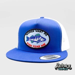 Puede incluir: Una gorra de camionero azul real con una malla blanca en la parte posterior. La gorra tiene un parche que dice "Women Want Me Fish Fear Me" con un pez de dibujos animados en él.
