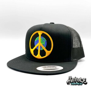 May include: Black trucker hat with a yellow peace sign featuring a blue and green globe in the center. The hat has a black mesh back.