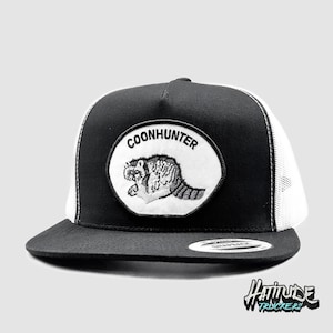 Puede incluir: Gorra de camionero negra y blanca con una parte trasera de malla blanca. La gorra tiene un parche bordado negro con un mapache y el texto "COONHUNTER".