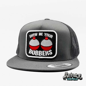 May include: A gray trucker hat with a black patch that says "Show Me Your Bobbers" with two red and white bobbers on it.