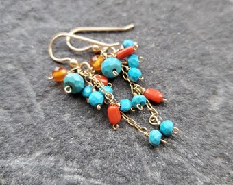 May include: Gold dangle earrings with turquoise and coral beads. The earrings have a chain design with multiple beads.