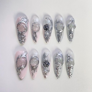 May include: Ten silver and white nail art designs with a floral and crystal theme. Each design features a different crystal and floral embellishment.