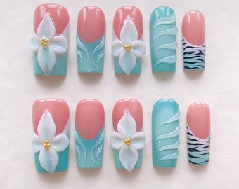 May include: Set of ten false nails with a variety of designs.  The nails are painted in shades of pink and blue. Some nails feature a 3D flower design, while others have a swirl or zebra print design.