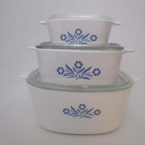 May include: A set of three ceramic mugs with a speckled, matte finish in cream, light grey, and dark grey. Each mug has a simple, modern design and a rounded handle.