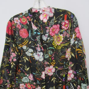 May include: A black long-sleeved button-up shirt with a colorful floral and geometric print. The shirt has a V-neck and a button-up front.