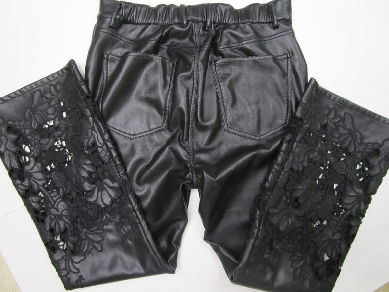 Pu&ograve; includere: Pantaloni in ecopelle nera con elastico in vita e due tasche posteriori. La parte inferiore delle gambe dei pantaloni &egrave; caratterizzata da intricati intagli in pizzo floreale nero che si estendono verticalmente lungo i lati del capo.