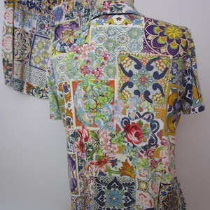 Puede incluir: Un conjunto de camisa de manga corta con botones y pantalones cortos a juego con un estampado de patchwork vibrante y multicolor. El patr&oacute;n consiste en varios dise&ntilde;os de azulejos geom&eacute;tricos, motivos florales y volutas intrincadas en tonos azul, amarillo, rojo, verde y morado sobre un fondo blanco.