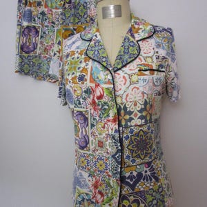 Puede incluir: Un conjunto de camisa de manga corta con botones y pantal&oacute;n corto a juego, con un patr&oacute;n de patchwork multicolor de azulejos florales y geom&eacute;tricos en tonos azul, amarillo, rojo y verde, acabado con ribetes negros en el cuello y bolsillo.