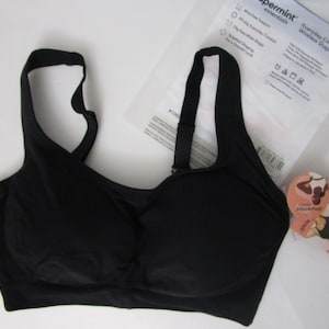 May include: A black wireless shaping bra with wide straps. The bra has a smooth design and is made of a soft material. The packaging includes the text "peppermint essentials" and "Everyday Comfort Straps Wireless Shaping Bra".