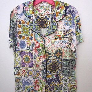 Puede incluir: Una camisa de pijama de manga corta con botones y un patr&oacute;n de azulejos multicolor en tonos azul, amarillo, verde y rojo. La camisa cuenta con un cuello de solapa, un bolsillo en el pecho y ribetes negros a lo largo de los bordes.