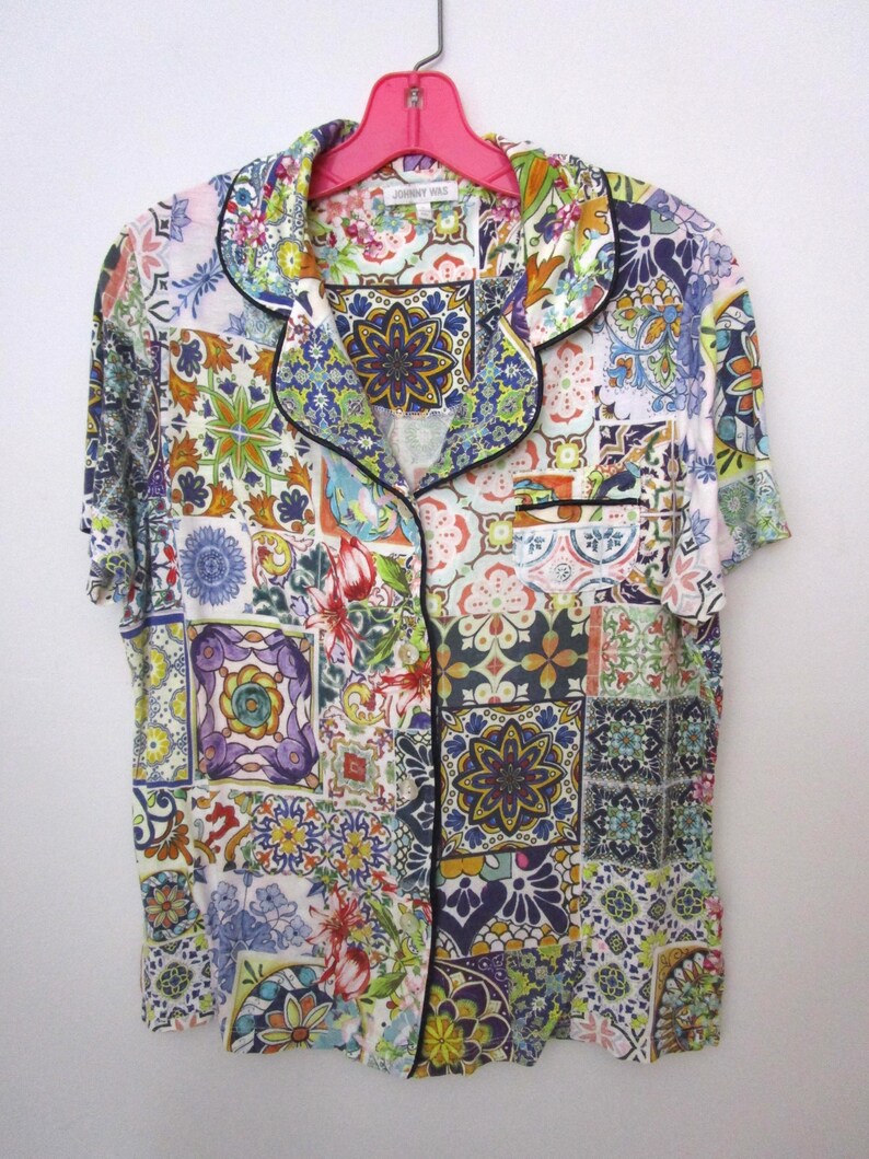 Puede incluir: Una camisa de pijama de manga corta con botones y un patr&oacute;n de azulejos multicolor en tonos azul, amarillo, verde y rojo. La camisa cuenta con un cuello de solapa, un bolsillo en el pecho y ribetes negros a lo largo de los bordes.