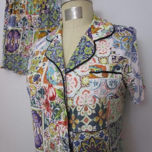 Puede incluir: Un conjunto de pijama de camisa de manga corta con botones y pantal&oacute;n corto a juego, con un estampado multicolor inspirado en azulejos. La camisa incluye un cuello con solapa y ribetes oscuros, un bolsillo en el pecho y cierre frontal.