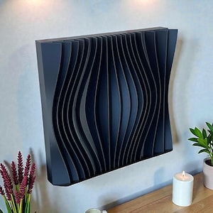 May include: A dark blue, wave-patterned wall panel. The panel has a series of vertical, curved lines that create a three-dimensional effect. The panel is mounted on a light-colored wall. A candle and plant are on a wooden surface below.