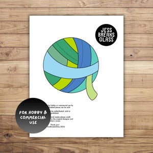 May include: A colourful yarn ball with blue, green and yellow stripes. The yarn ball is on a white background with the text "Jess Breaks Glass" and "For Hobby & Commercial Use" in black text.