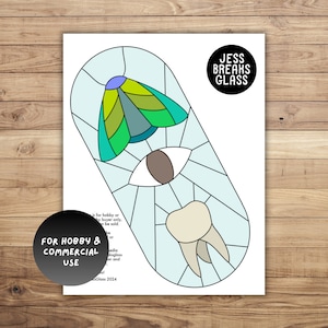 May include: A stained glass pattern design featuring a blue, green, and yellow moth, a brown eye, and a white tooth. The design is outlined in black and set against a light blue background. The text "JESS BREAKS GLASS" is in a black circle at the top of the image. The text "FOR HOBBY & COMMERCIAL USE" is in a black circle at the bottom of the image.
