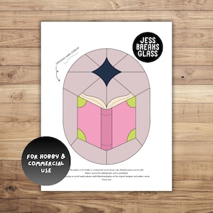 May include: A printable stained glass pattern featuring a book with a pink cover and green accents. The pattern is titled "Jess Breaks Glass" and is for hobby and commercial use.