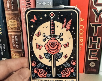 May include: A black and white illustration of a sword through a red rose with a full moon and butterflies in the background. The text "ROMANTASY BOOK CLUB" is at the bottom of the card.