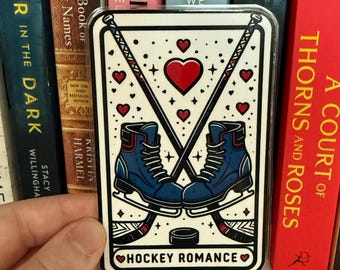 May include: A rectangular sticker with a hockey theme. It features two blue ice skates, crossed hockey sticks, a red heart, and the words "HOCKEY ROMANCE." The background is white with small red hearts.