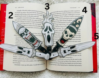 May include: Five different bookmark designs featuring a variety of horror movie characters. The bookmarks are shaped like knives and feature a skull, a ghost, and a scream mask.