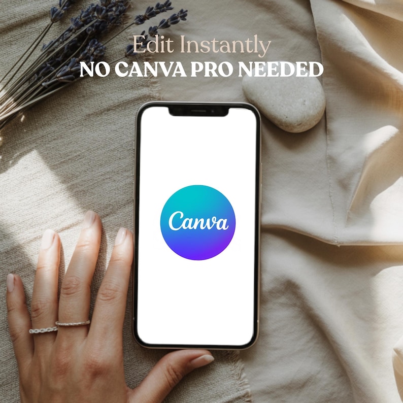May include: A smartphone displays the Canva logo, a gradient circle of teal and purple. Text above reads "Edit Instantly, NO CANVA PRO NEEDED." The phone rests on a beige fabric, with a sprig of lavender and a small stone nearby.