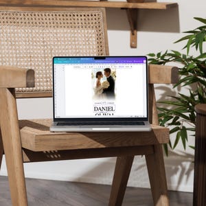 Peut inclure: Un ordinateur portable affichant une maquette de faire-part de mariage avec un couple en tenue de c&eacute;r&eacute;monie. L'invitation comprend les noms "DANIEL" et "OLIVIA" en police serif. L'ordinateur est pos&eacute; sur une chaise en bois avec une assise tress&eacute;e, avec une plante en arri&egrave;re-plan.